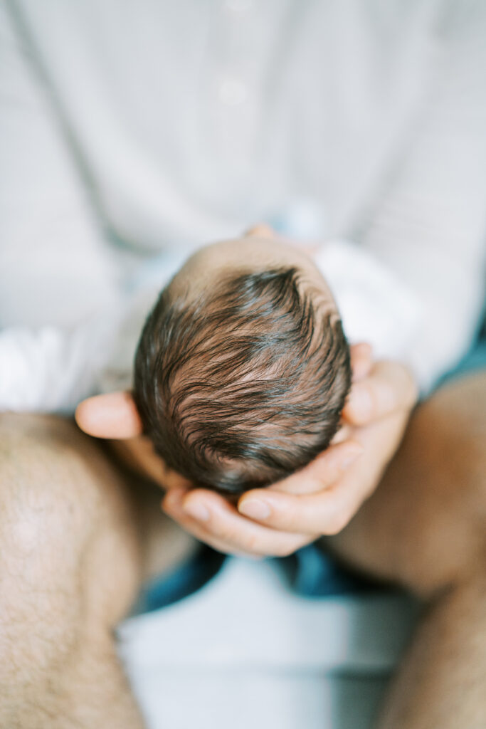 father holding his baby's head in his hands