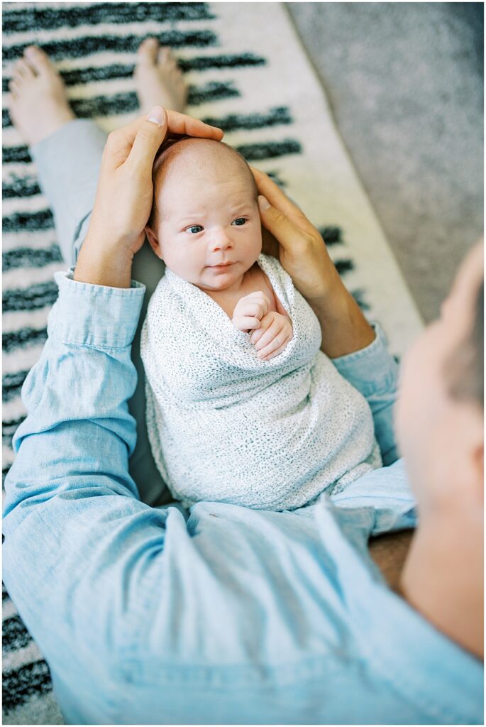 father holding swaddled baby during newborn photography session