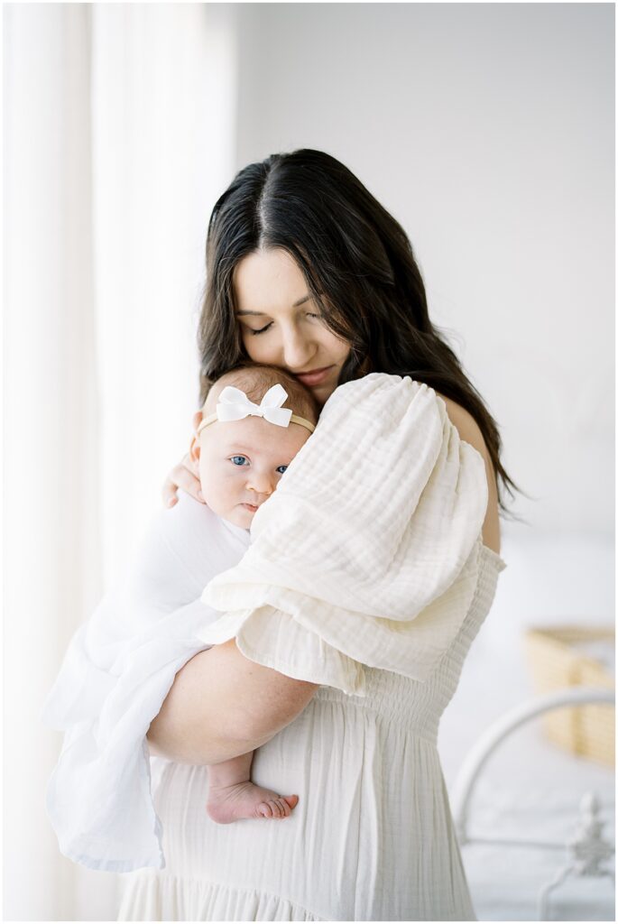 mother snuggling swaddled baby during studio newborn photography session