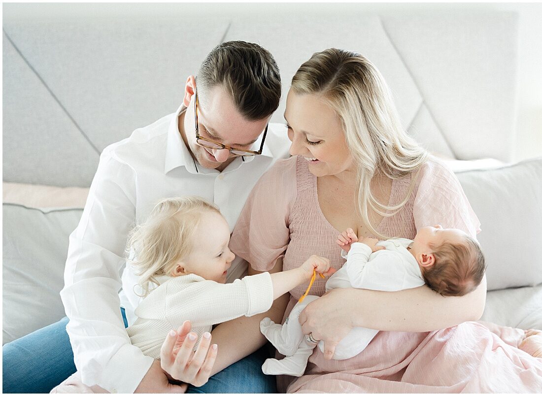 family laughing on a bed during newborn photos