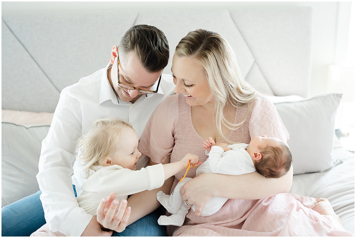 family laughing on a bed during newborn photos