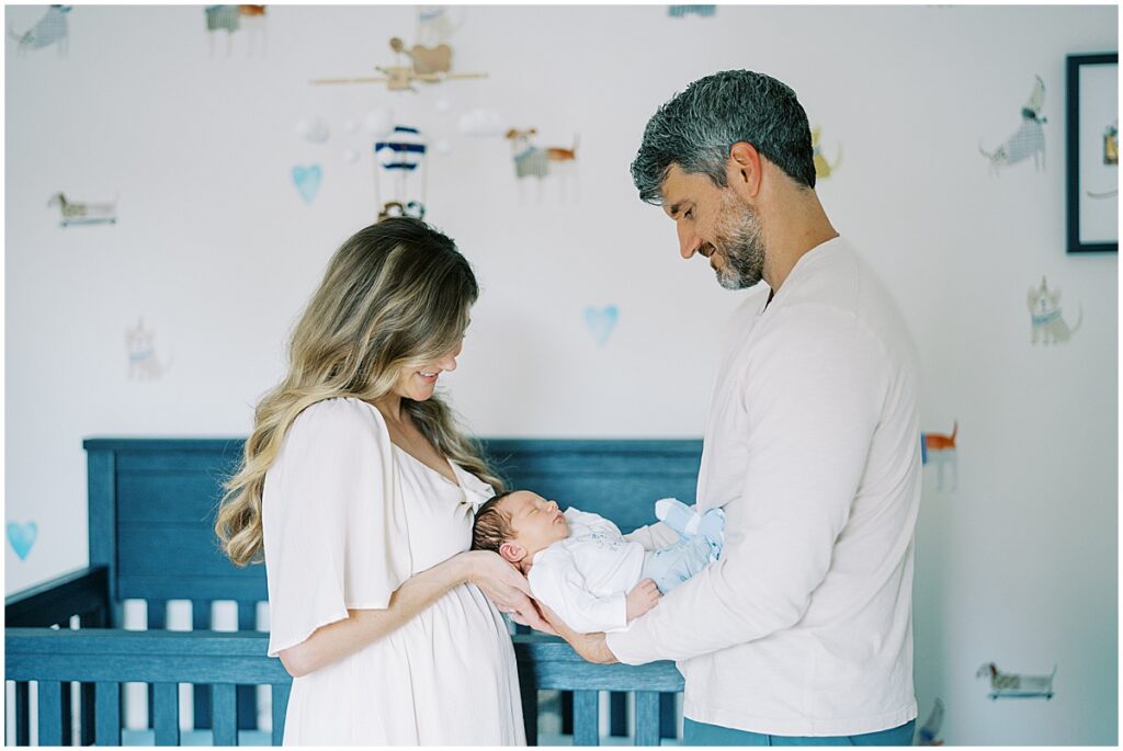 mother and father holding their newborn baby between them during a lifestyle newborn photo session