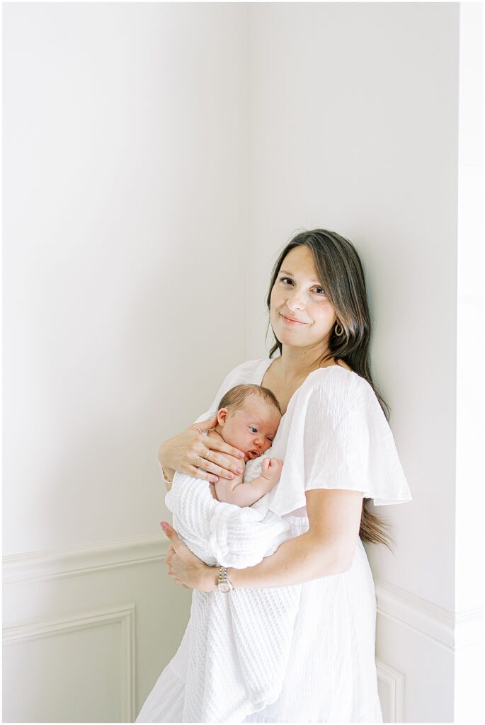 Mother holds newborn in all white studio session