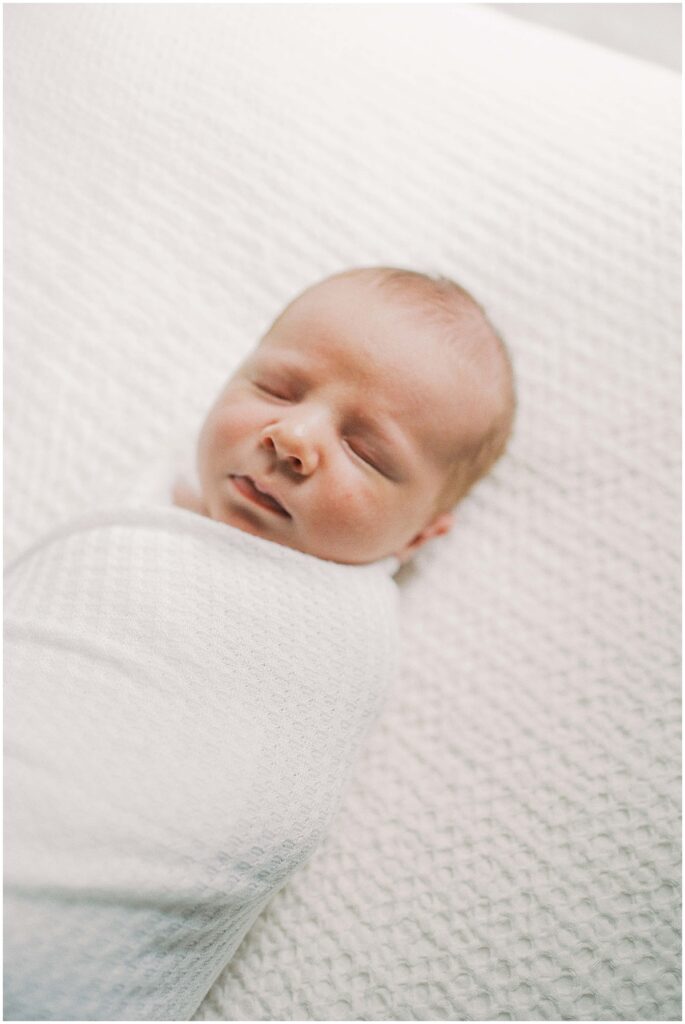 Baby swaddled on white blanket in newborn session