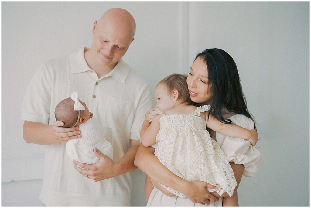 Family of four admire newborn during studio session