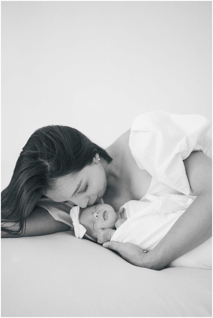 Mom holds newborn with white bow in Indianapolis studio session