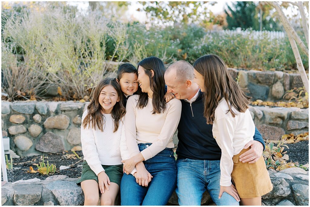 Family sits on stone steps in front of yellow fall leaves in Indianapolis