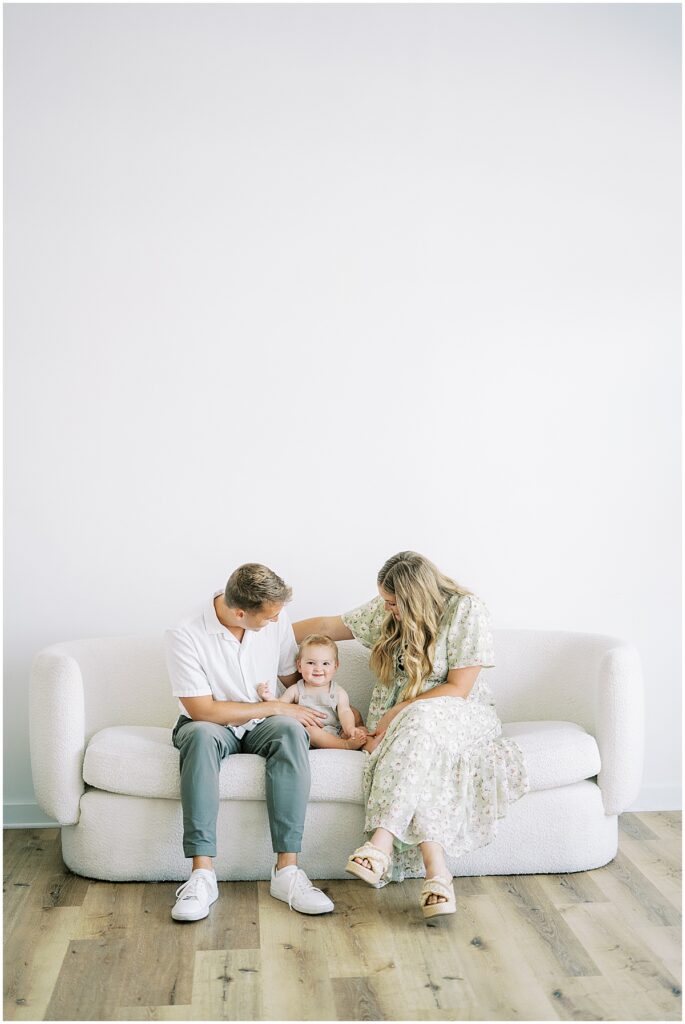 Mom and dad with child on couch during studio session in Indianapolis