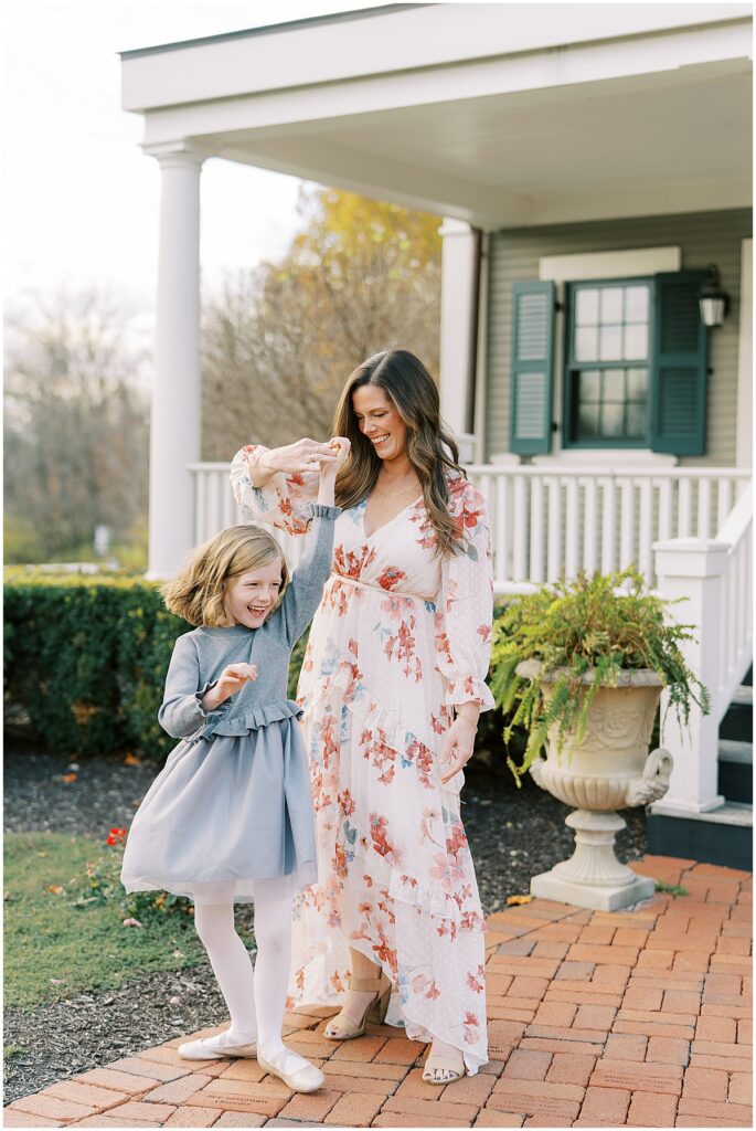 Mom spins daughter outside The Ambassador House during fall mini session