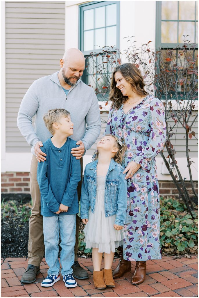 Family of four wearing blue outside The Ambassador House during fall mini session
