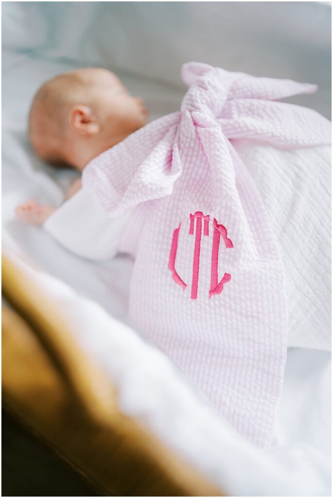 Newborn girl wrapped in monogrammed bow blanket during studio photos in Indianapolis