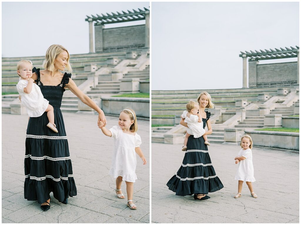 Mother in black dress dances with daughters in white dresses by Coxhall Gardens architecture
