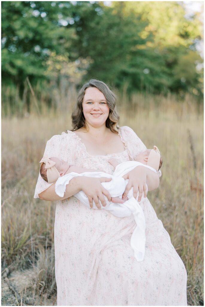 Mom in light pink holds twin daughters during spring photo session