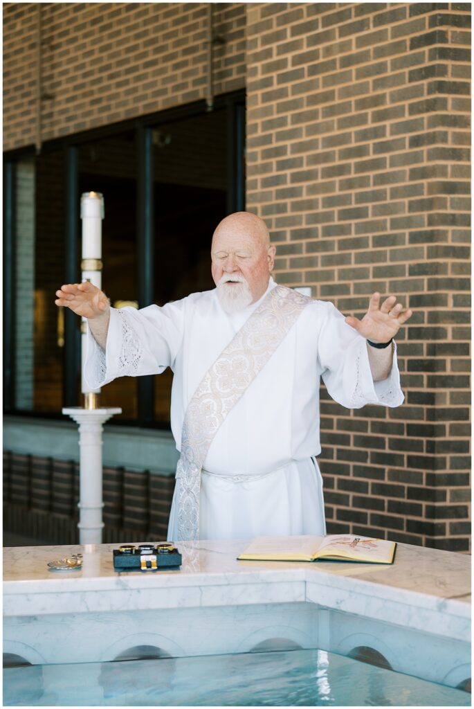 Priest praying over baptismal font before baptism in Carmel Indiana