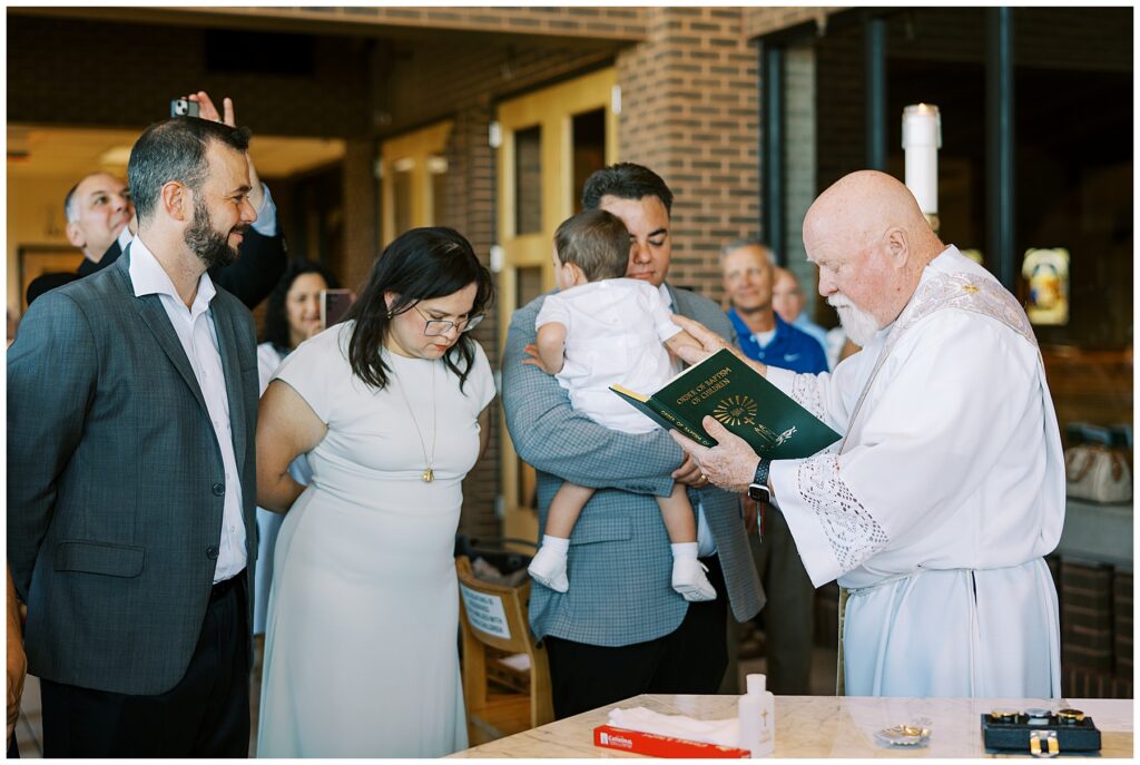 Priest prays over child during baptism in Carmel Indiana