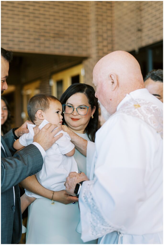 Priest prays over child during baptism in Carmel Indiana