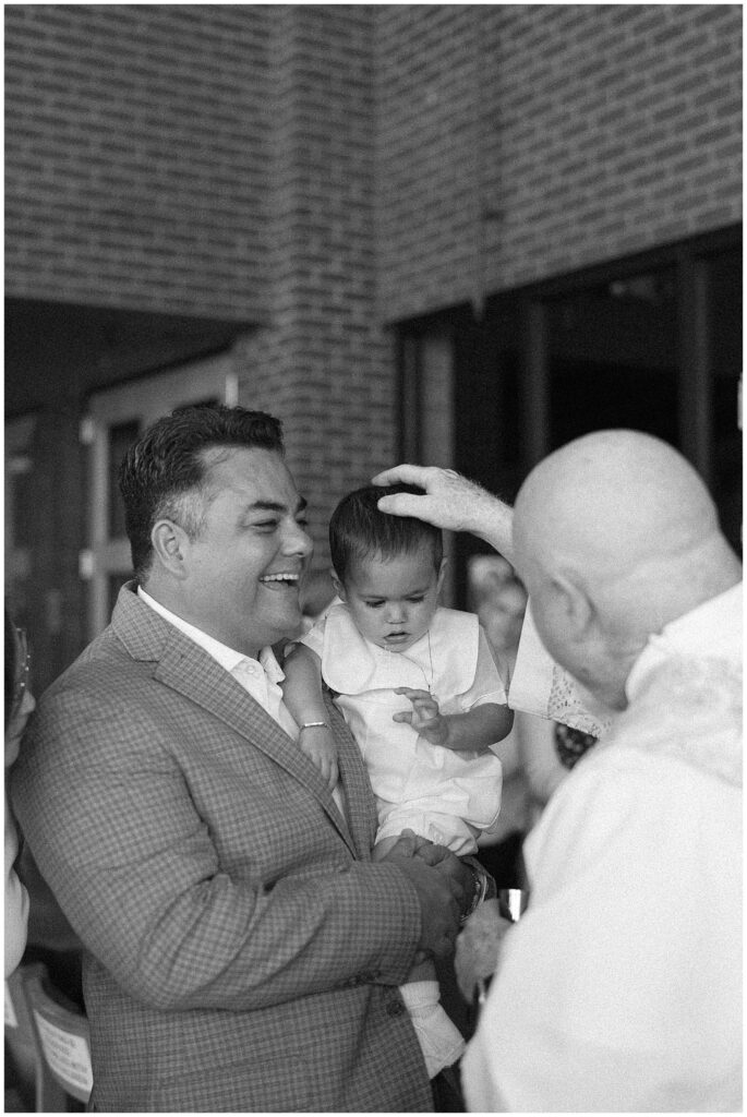 Priest prays over child during baptism in Carmel Indiana