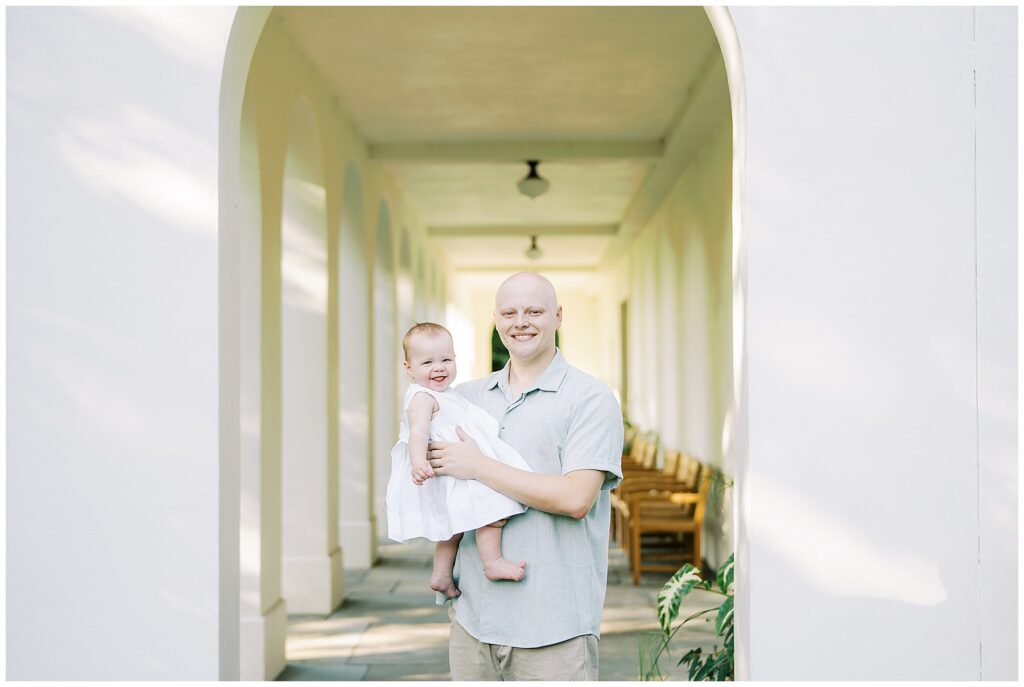 Father and daughter under archways during outside milestone session