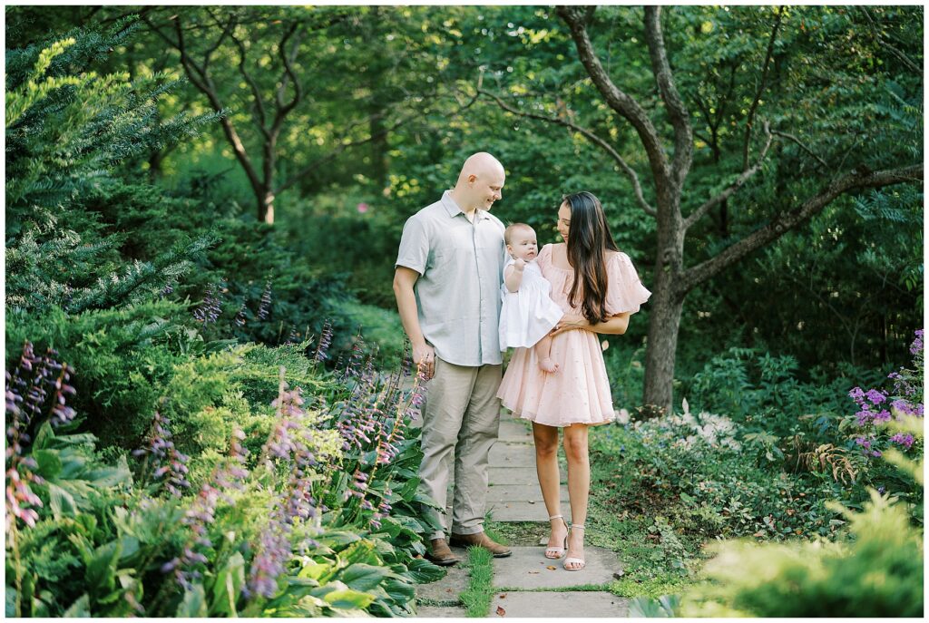 Family of three walk on garden path during milestone session