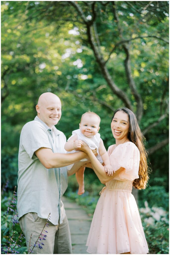 Family of three walk on garden path during milestone session