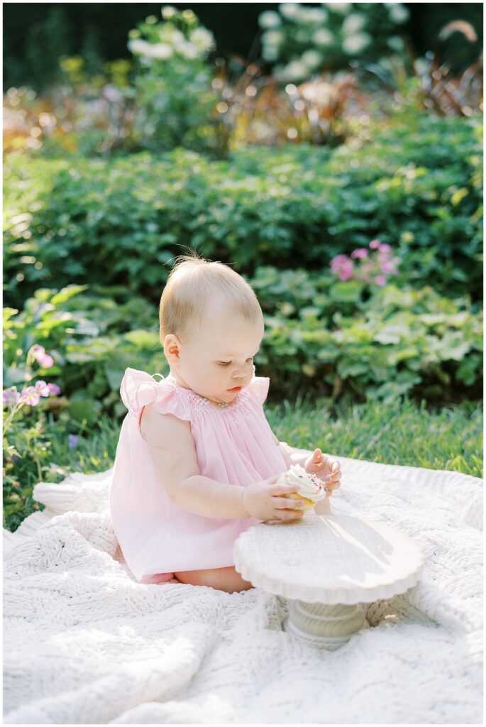Cake smash session with cupcake in garden during first birthday milestone photo session in Indianapolis